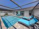 Sparkling pool with sun loungers under a screened enclosure, perfect for outdoor entertainment and relaxation at 1231 Pine Needle Rd, Venice, FL 34285
