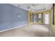Bedroom with tray ceiling, carpet, large window and doorway to the lanai at 1241 Creek Nine Dr, North Port, FL 34291