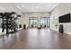 Bright fitness studio with hardwood floors, fitness equipment, a mirrored wall, and a large TV for classes at 12418 Asana Ct, Venice, FL 34293