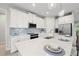 Contemporary kitchen with white cabinetry, island with seating, stainless appliances, and stylish pendant lights at 12418 Asana Ct, Venice, FL 34293