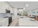 Modern kitchen featuring white cabinets, quartz countertops, stainless steel appliances, and an island at 12418 Asana Ct, Venice, FL 34293