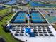 Aerial view of a community with tennis courts, garden plots, parking, and picturesque waterways at 13150 Huerta St, Venice, FL 34293