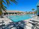 Luxurious community pool with lounge chairs and palm trees in a tropical setting on a clear day at 13150 Huerta St, Venice, FL 34293