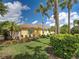 Charming yellow home with a red tile roof, lush landscaping, and elegant palm trees against a blue sky at 13150 Huerta St, Venice, FL 34293