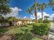 Charming yellow home with a red tile roof, lush landscaping, and elegant palm trees against a blue sky at 13150 Huerta St, Venice, FL 34293