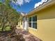 Charming home exterior with a brick walkway, lush landscaping, and a vibrant yellow facade at 13150 Huerta St, Venice, FL 34293