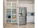 Open pantry with pull-out shelves beside a stainless steel refrigerator in this well-equipped kitchen at 13150 Huerta St, Venice, FL 34293