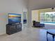 Open-concept living room featuring tile flooring, modern lighting, and an entertainment center with a flat-screen TV at 13150 Huerta St, Venice, FL 34293