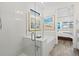 Spa-like bathroom features a soaking tub and glass shower enclosure, leading to a bedroom with shuttered windows at 13511 Esposito St, Venice, FL 34293