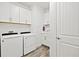 Bright laundry room features modern washer and dryer, white cabinets, and wood-look flooring at 13511 Esposito St, Venice, FL 34293