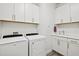 Well-equipped laundry room featuring a modern washer and dryer, along with ample storage cabinets and sink at 13511 Esposito St, Venice, FL 34293