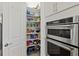 Walk-in pantry offering ample storage space adjacent to stainless steel ovens for convenient access at 13511 Esposito St, Venice, FL 34293