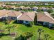 Aerial view showcases the home's backyard, mature palm trees, landscaping, and tiled roof in a lovely community at 13872 Rinuccio St, Venice, FL 34293