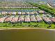 An aerial view captures a street lined with houses and palm trees near a serene lake in this beautiful community at 13872 Rinuccio St, Venice, FL 34293