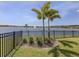 A well-maintained backyard with lake view, palm trees, and black aluminum fence at 149 Vinadio Blvd, Nokomis, FL 34275