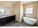 Bathroom featuring soaking tub, dual sinks, granite countertops, window and hardwood floors at 1510 Haffenberg Ave, North Port, FL 34288