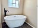 Bathroom featuring soaking tub, window, hardwood floors and dark faucet at 1510 Haffenberg Ave, North Port, FL 34288