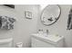 Close up of a bathroom sink with gray walls and a round mirror at 1629 Siesta Dr, Sarasota, FL 34239