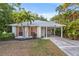 Beautiful single-story home with light gray roof, manicured lawn, shuttered windows, and a covered entryway at 1629 Siesta Dr, Sarasota, FL 34239