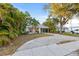 Charming single-story home with a light gray roof, a covered parking area, and a beautifully landscaped front yard at 1629 Siesta Dr, Sarasota, FL 34239