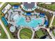 Aerial view of a resort-style pool and lounge area with blue umbrellas, palm trees, and ample seating at 17324 Sandpearl Rd, Venice, FL 34293