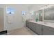 Bright bathroom with double vanity, large mirror, and gray cabinetry at 17324 Sandpearl Rd, Venice, FL 34293