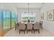 Well-lit dining room with contemporary chandelier, seating for eight, and a large window at 17324 Sandpearl Rd, Venice, FL 34293