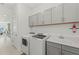 Convenient laundry room featuring modern appliances, utility sink, overhead cabinets, and easy access at 17324 Sandpearl Rd, Venice, FL 34293