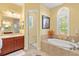Bright bathroom featuring a soaking tub, dark wood cabinets, and decorative flower arrangement at 20126 Elegante Ct, Venice, FL 34293
