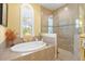Bright bathroom showcasing a soaking tub under an arch window and glass shower enclosure at 20126 Elegante Ct, Venice, FL 34293