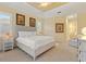 Bright bedroom with white bedding, side table, and sitting area, showcasing tray ceiling at 20126 Elegante Ct, Venice, FL 34293
