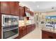 Modern kitchen with stainless steel appliances, tiled backsplash, and a view of the outdoor space at 20126 Elegante Ct, Venice, FL 34293