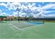Community tennis court with lighting, shade, and green and blue surfacing at 20126 Elegante Ct, Venice, FL 34293