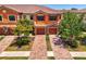 Charming two-story townhome featuring a clay tile roof, brick driveway, and attached two-car garage at 20237 Lagente Cir, Venice, FL 34293