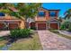 Inviting townhome featuring a clay tile roof, brick paved driveway and lush landscaping at 20237 Lagente Cir, Venice, FL 34293
