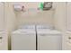 Well-lit laundry room with white washer and dryer, and shelving above for storage at 20237 Lagente Cir, Venice, FL 34293