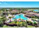 Aerial view of a large community pool surrounded by palm trees, with red umbrellas and lounge chairs at 20237 Lagente Cir, Venice, FL 34293