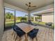 This covered patio features an outdoor dining set and a lounge chair and a ceiling fan at 20285 Symphony Pl, Venice, FL 34293