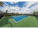 Well-maintained tennis court with blue and green surface, surrounded by black fencing and lush greenery at 20285 Symphony Pl, Venice, FL 34293