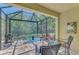 Screened-in patio featuring tile flooring, seating, table, and an outdoor grill overlooking a lush, green backyard at 20290 Lagente Cir, Venice, FL 34293