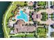 Aerial view of a resort-style pool, red umbrellas, lush landscaping, and tile roof buildings at 20290 Lagente Cir, Venice, FL 34293
