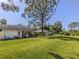 Large backyard with mature trees, manicured lawn, and screened-in lanai at 229 Southampton Drive # 290, Venice, FL 34293