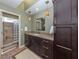 Bathroom with vanity, dark cabinetry, stone countertop, decorative pendants, and tiled shower at 229 Southampton Drive # 290, Venice, FL 34293