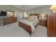 Main bedroom with large bed, side tables, a dresser, and closet with neutral carpeting at 229 Southampton Drive # 290, Venice, FL 34293