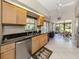 Bright kitchen with stainless appliances, stone countertops, tile floors, and natural wood cabinetry at 229 Southampton Drive # 290, Venice, FL 34293