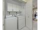 White laundry room with front loading washer and dryer, white cabinets, and tile floors at 229 Southampton Drive # 290, Venice, FL 34293