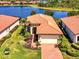 Aerial view of a terracotta-roofed home with beautiful landscaping near a scenic lake at 23494 Copperleaf Dr, Venice, FL 34293