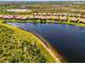 Aerial view of lakeside home with a tile roof and lush green landscaping at 23494 Copperleaf Dr, Venice, FL 34293