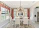 Elegant dining area with tray ceiling, modern chandelier, and views to the exterior through shuttered windows at 23494 Copperleaf Dr, Venice, FL 34293