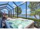 Relaxing screened-in lanai with a hot tub overlooking the tranquil lake view at 23494 Copperleaf Dr, Venice, FL 34293